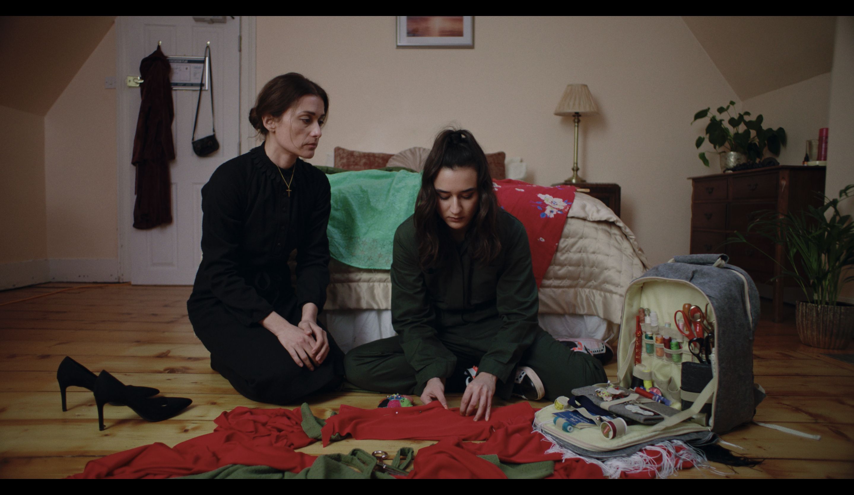 Mother watches daughter sew.