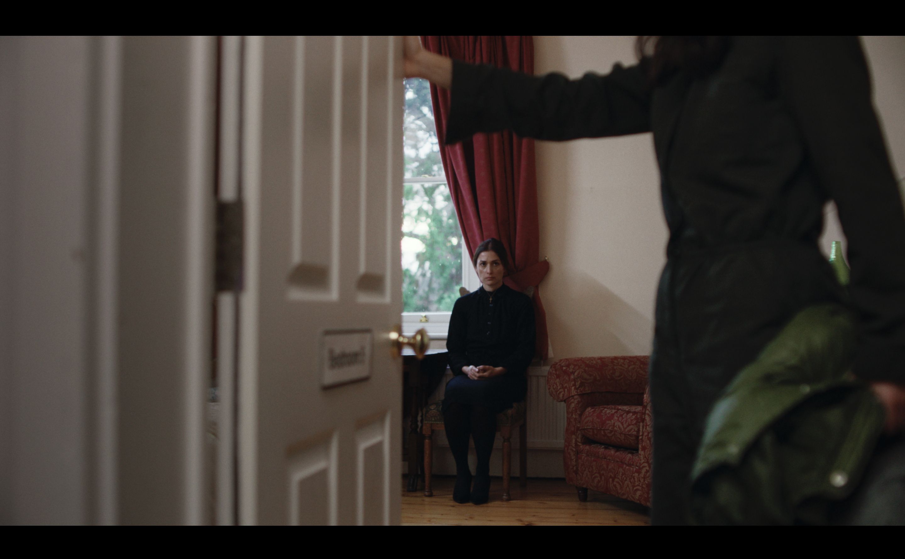 Daughter opens door. Mother sits.